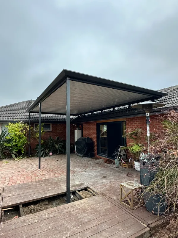 Black flat patio roof connected to the existing tiled roof