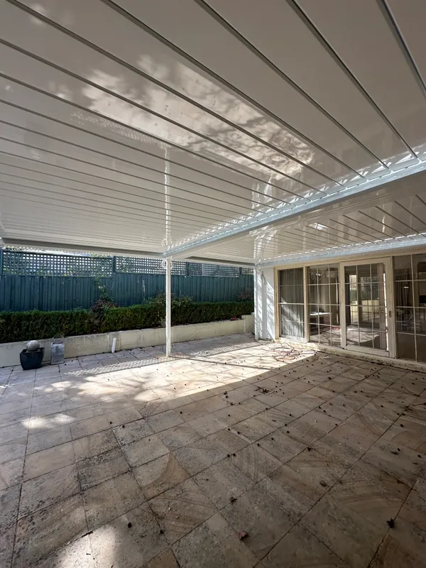 Adjustable white louvres casting filtered light over the courtyard